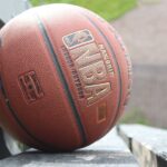 A detailed image showcasing a basketball resting on a park bench, highlighting texture and outdoor setting.