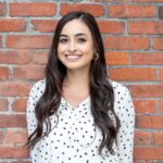 Confident woman posing in front of a brick wall, exuding professionalism.