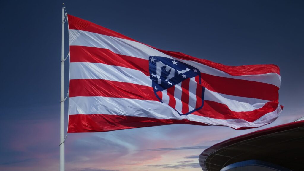 Waving Atlético Madrid flag against a sunset sky, symbolizing team spirit in Madrid.