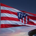 Waving Atlético Madrid flag against a sunset sky, symbolizing team spirit in Madrid.