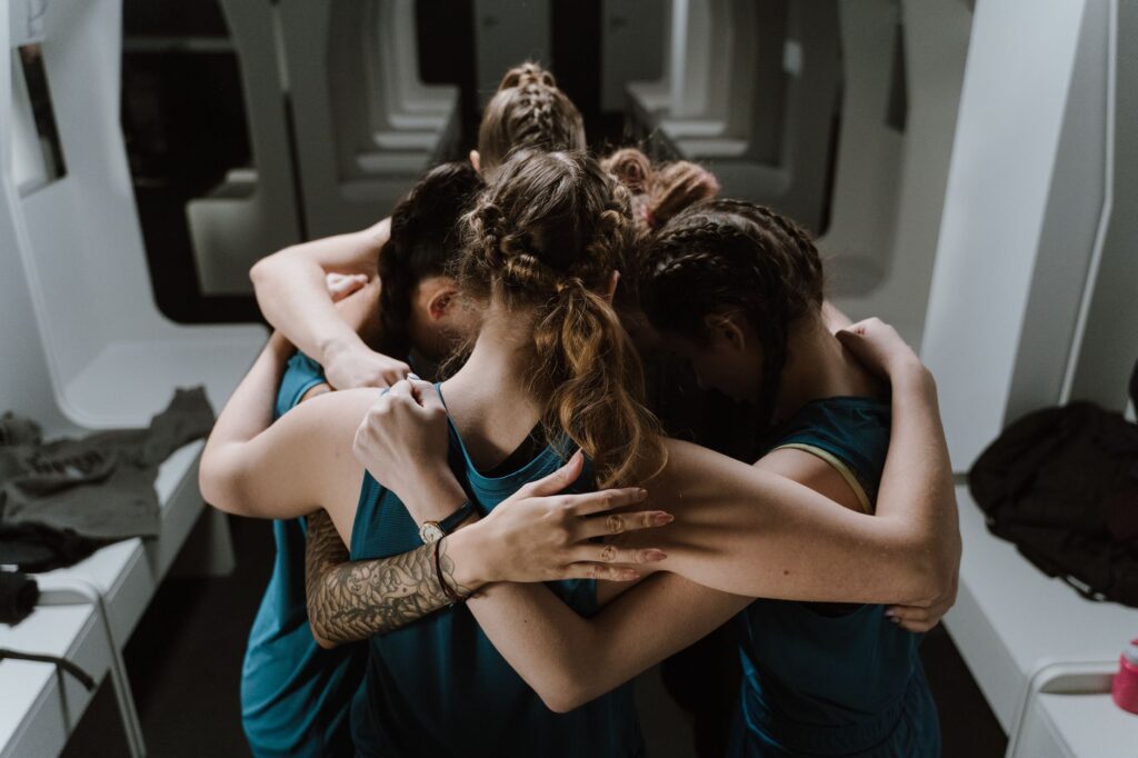 A group of athletes in a united huddle, symbolizing teamwork and unity in a sports changing room.