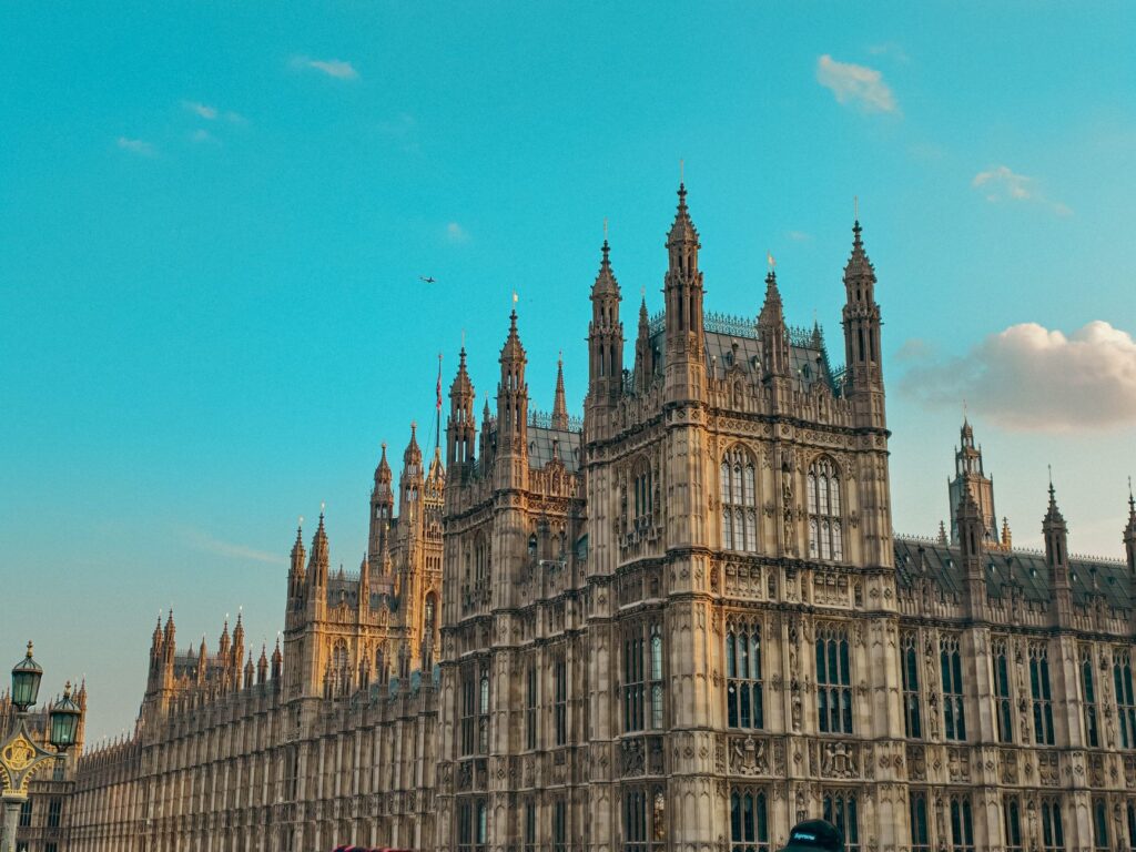 Gothic architecture of the Houses of Parliament against a clear blue sky in London.