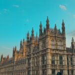 Gothic architecture of the Houses of Parliament against a clear blue sky in London.