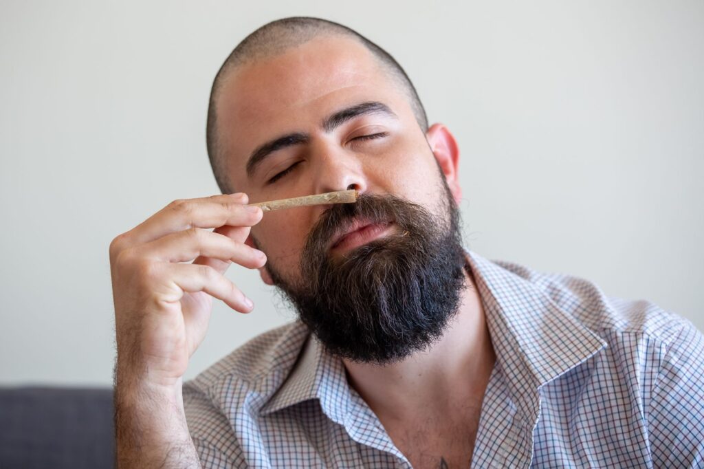 Close-up of a bearded man relaxing indoors with a joint, eyes closed, in Portugal.