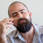 Close-up of a bearded man relaxing indoors with a joint, eyes closed, in Portugal.