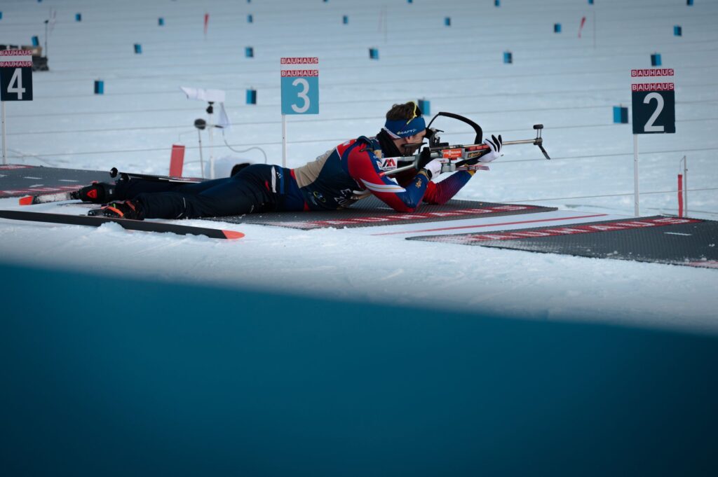 Biathlete competes in a snowy biathlon event, aiming with precision and focus.