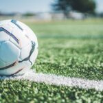 Soccer ball resting on white line of a green grass field. Perfect for sport themes.