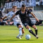 Two soccer players in action during a competitive outdoor match.