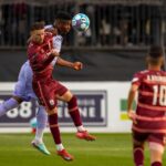 Players engage fiercely during a competitive soccer match, capturing a dynamic moment of athleticism.