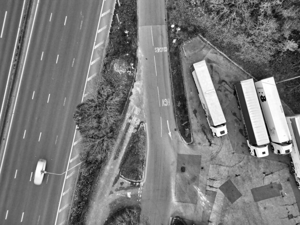 Aerial view of a highway intersection with parked trucks in black and white.