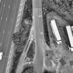 Aerial view of a highway intersection with parked trucks in black and white.