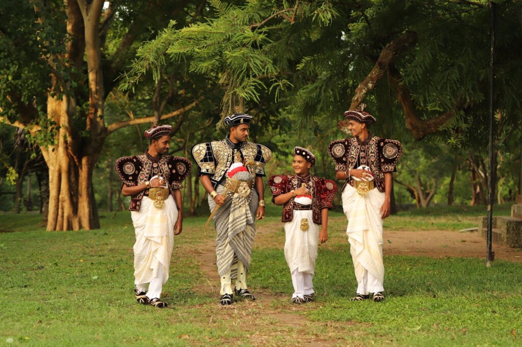 Men and boy in traditional Kandyan dress in a lush park setting, Sri Lanka.