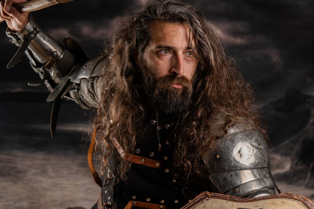 Bearded medieval warrior in armor and shield, poised for combat against a stormy backdrop.