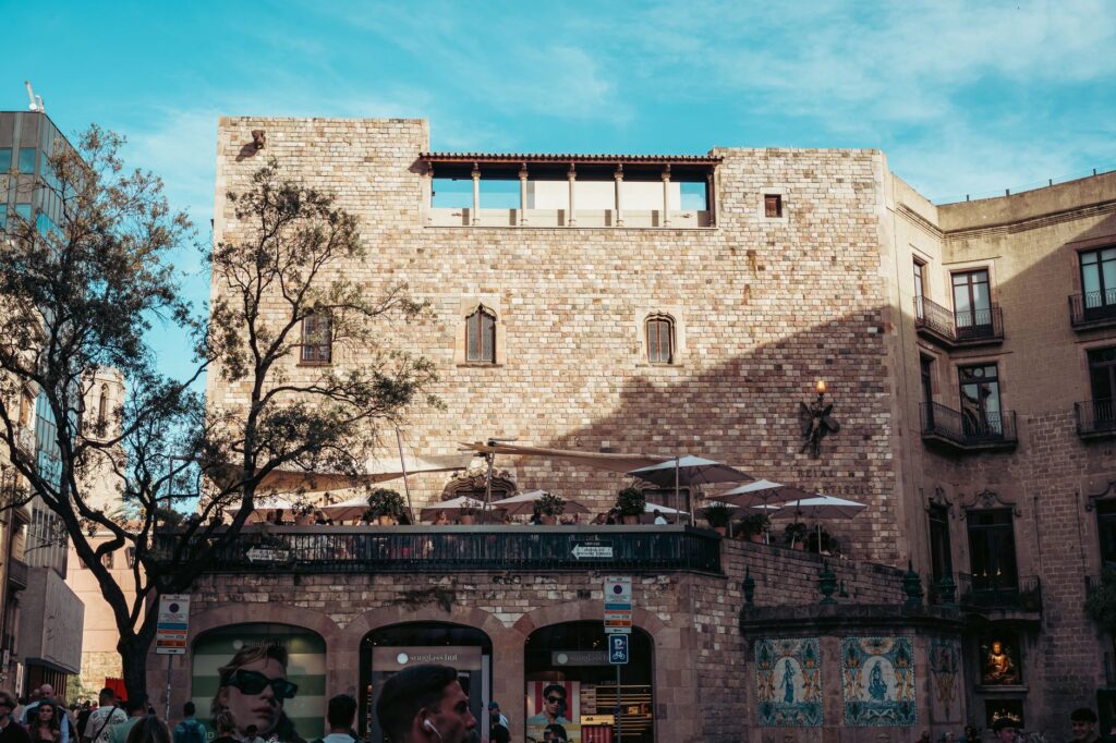 Sunlit historic stone building in Barcelona's urban plaza captured during a bright day.