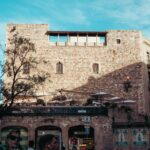 Sunlit historic stone building in Barcelona's urban plaza captured during a bright day.