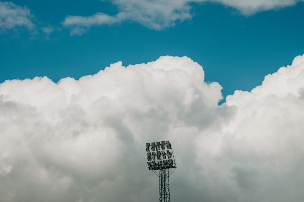 Stadium light tower stands against a backdrop of dramatic clouds and vivid blue sky in Jönköping.