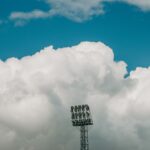 Stadium light tower stands against a backdrop of dramatic clouds and vivid blue sky in Jönköping.