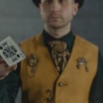 A magician displays the King of Spades card, creating intrigue and focus in a dimly lit scene.