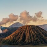 Sunrise over Mount Bromo in East Java, showcasing volcanic landscape and steam clouds.
