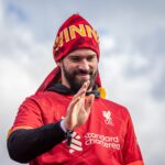 Liverpool FC player joyfully celebrates victory under the clear sky.