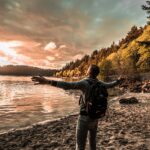 Man with arms outstretched, enjoying a scenic sunset by a lakeside in Bellingham, WA.