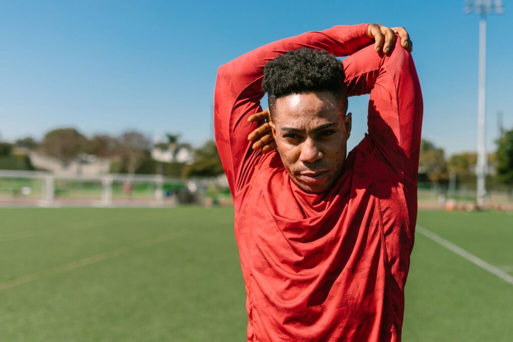 A young athlete stretching outdoors in sportswear on a sunny day.