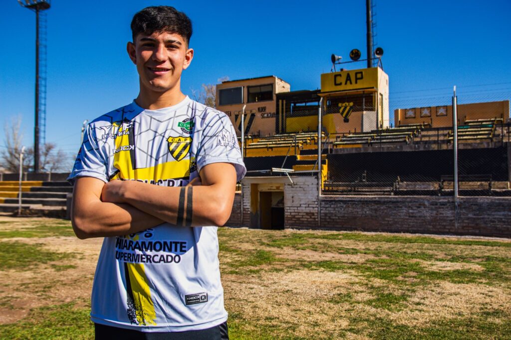 Smiling soccer player posing confidently in the stadium on a sunny day.