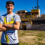 Smiling soccer player posing confidently in the stadium on a sunny day.