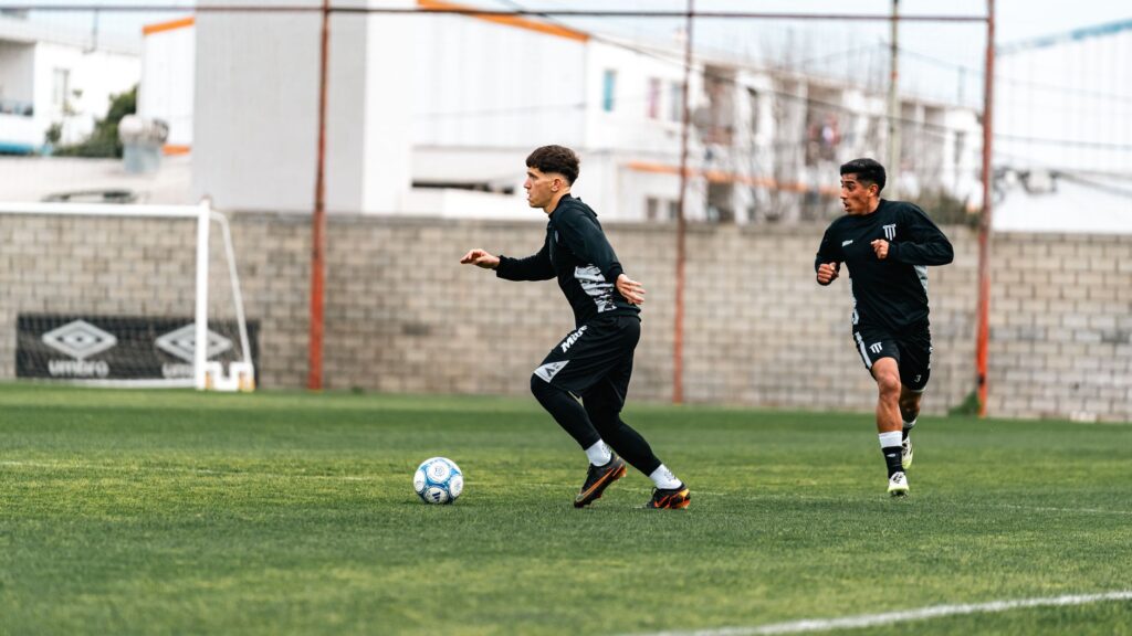 Two young men playing soccer on a field during a training session.