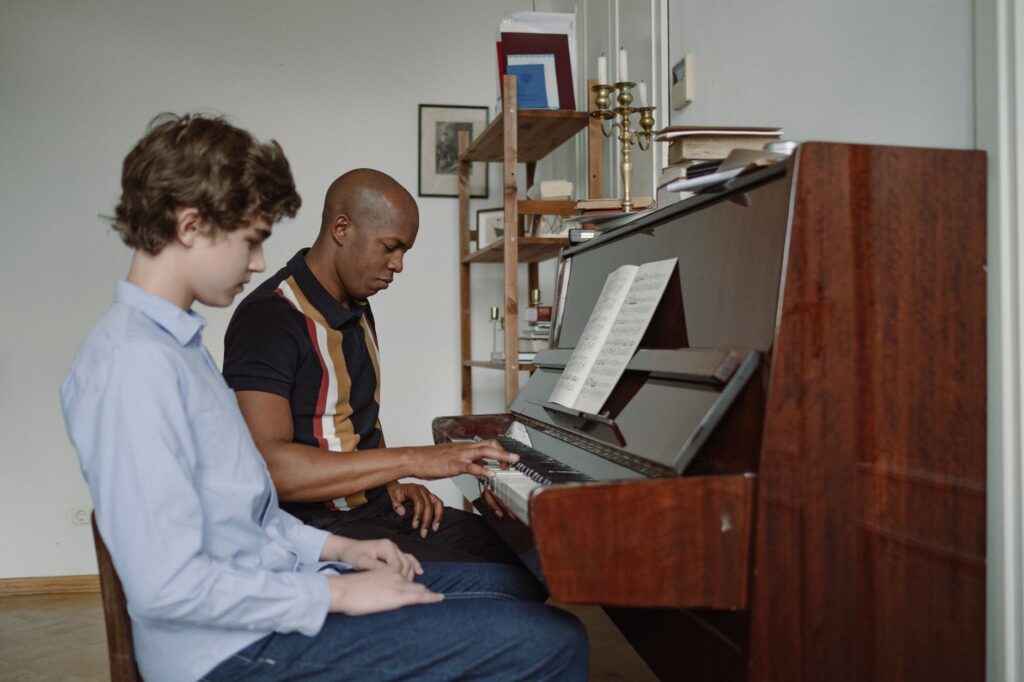 A serious music lesson with an adult teacher and young boy at a piano, focusing on piano practice.