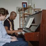 A serious music lesson with an adult teacher and young boy at a piano, focusing on piano practice.