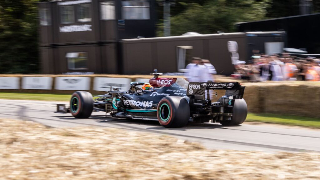Mercedes Formula One car racing at high speed on an outdoor track in England.