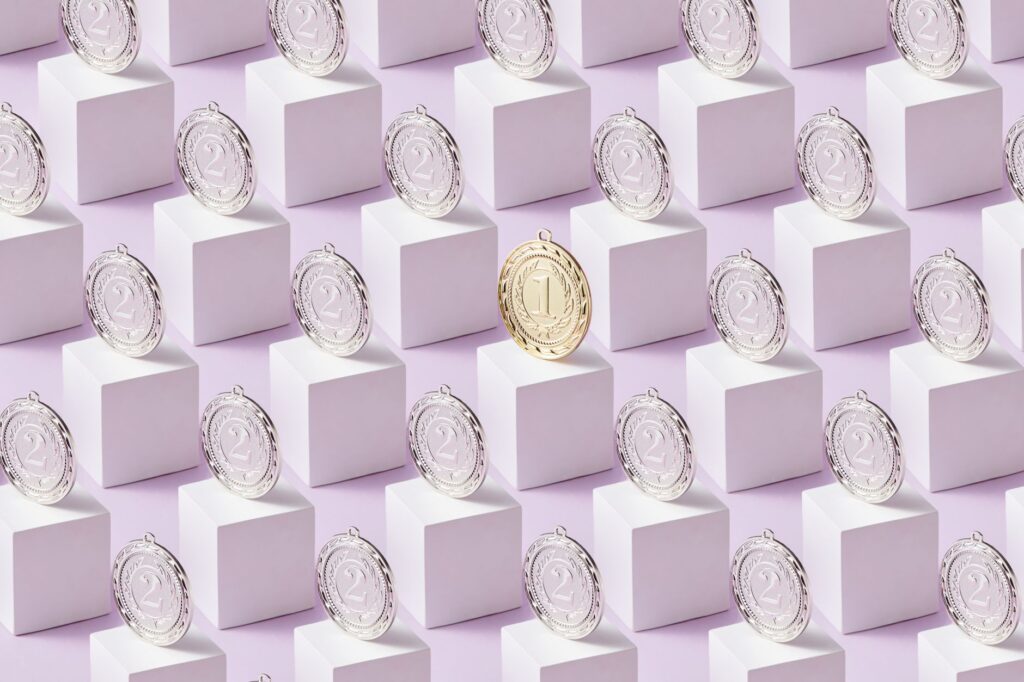 A gold medal stands out among silver medals on white cubes, showcasing uniqueness.