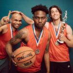 Three basketball players celebrating victory with trophies and medals, showcasing teamwork and accomplishment.