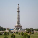 Stunning daytime capture of Minar-e-Pakistan surrounded by lush greenery in Lahore.