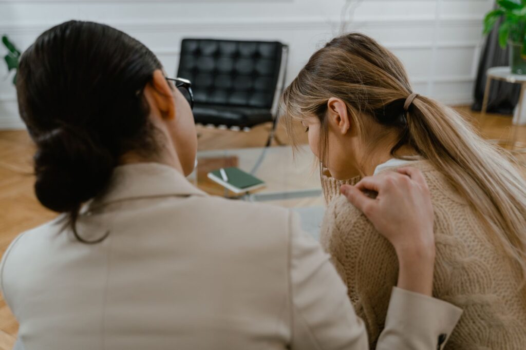 Two women sitting together, offering emotional support in a comforting setting.
