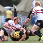 Rugby players in action during a competitive match on a grassy field.