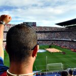 A passionate football fan cheers among a crowd at a bustling stadium, creating an electrifying atmosphere.