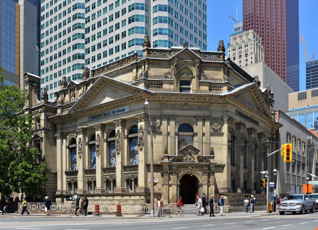 Explore the historic neoclassical facade of the Hockey Hall of Fame in Toronto's bustling cityscape.