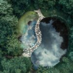 Aerial photograph showing a serene yin yang-shaped pond surrounded by lush greenery.