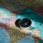 Close-up image of compass on a world map highlighting travel direction and exploration.