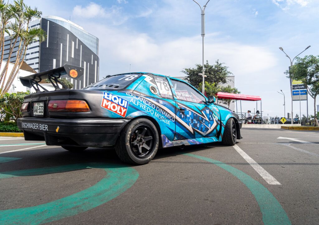 A colorful racing car with decals parked on a city street under a clear sky.