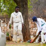 Cricket players in sportswear ready to start a match, showcasing camaraderie and focus in an outdoor setting.
