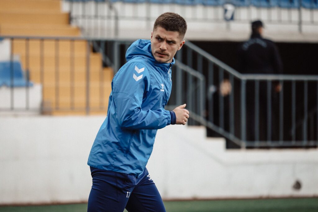 Focused football player warming up on the field in Baku, Azerbaijan, showcasing athletic determination.