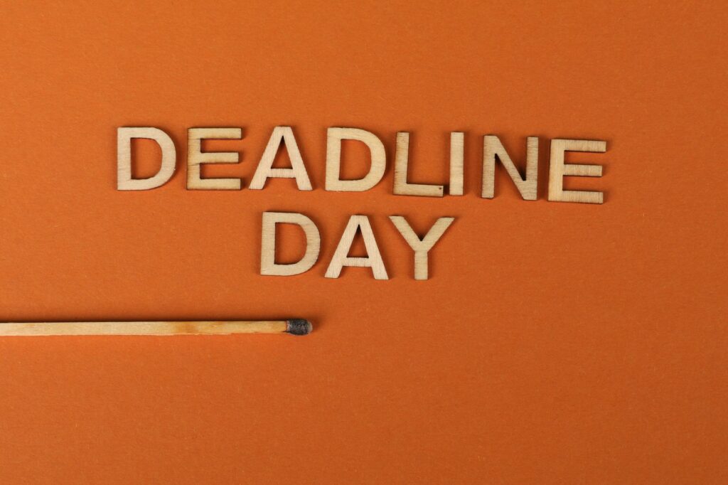 Conceptual image of a deadline with wooden letters and burnt matchstick on orange background.