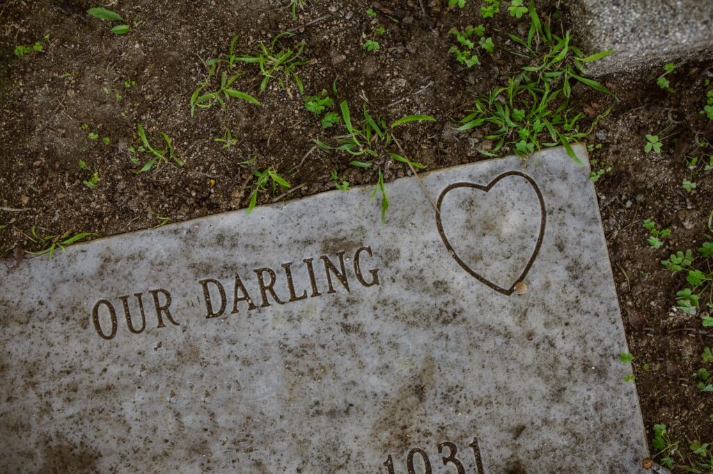 Detailed shot of a gravestone engraved with 'Our Darling' and a heart symbol.