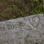 Detailed shot of a gravestone engraved with 'Our Darling' and a heart symbol.