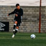 A young male soccer player practicing on a grass field, focusing on a precise kick.