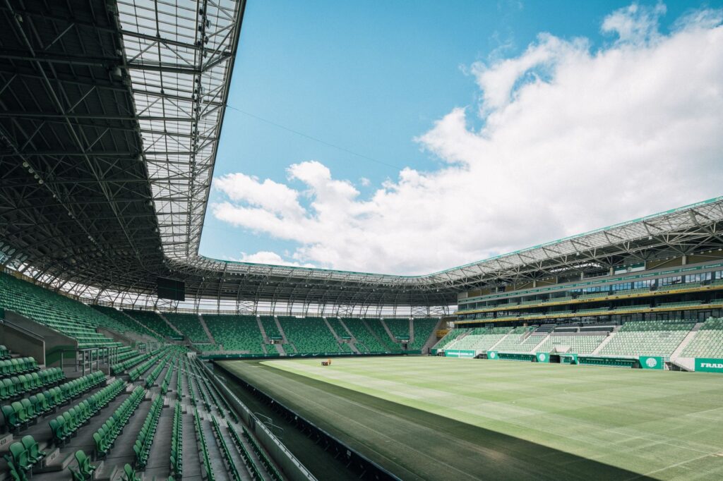 View of a modern stadium in Budapest, Hungary, showcasing green seats and a vast open sky.