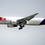 FedEx Boeing aircraft flying against a clear sky, showcasing air freight services.